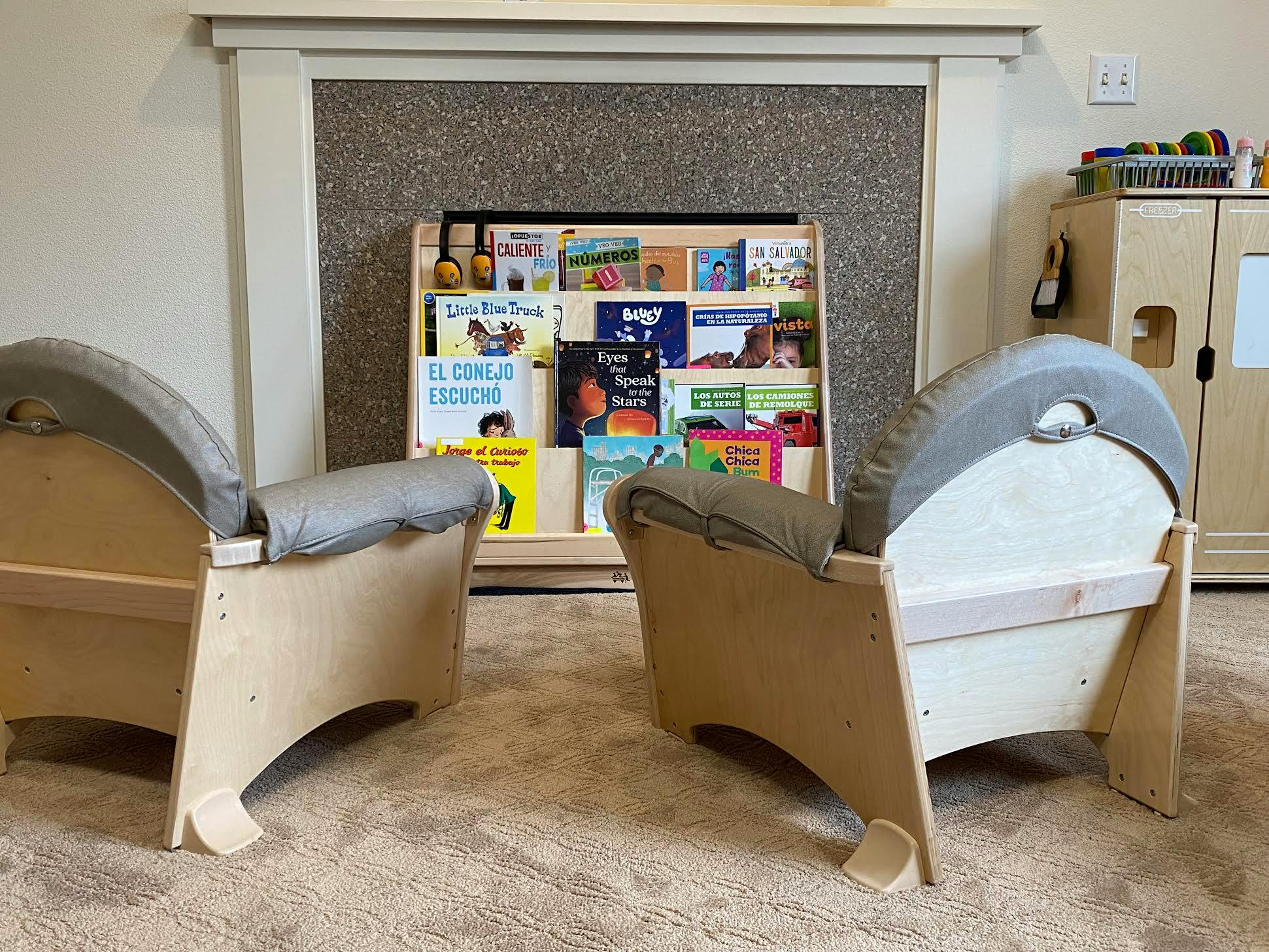 Two small chairs facing a bookshelf filled with children's books