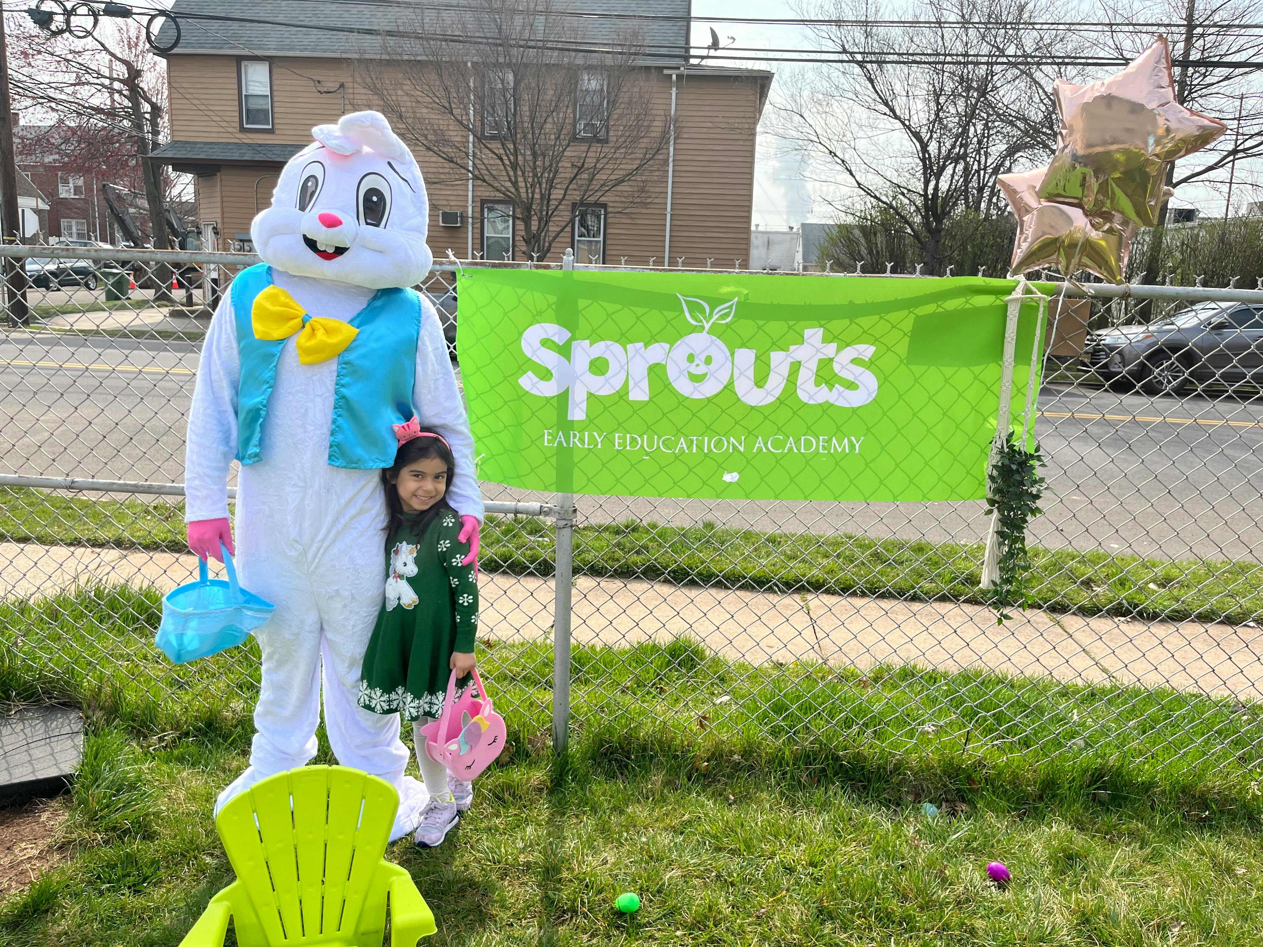 Person in bunny costume with a child holding baskets next to a "Sprouts" banner