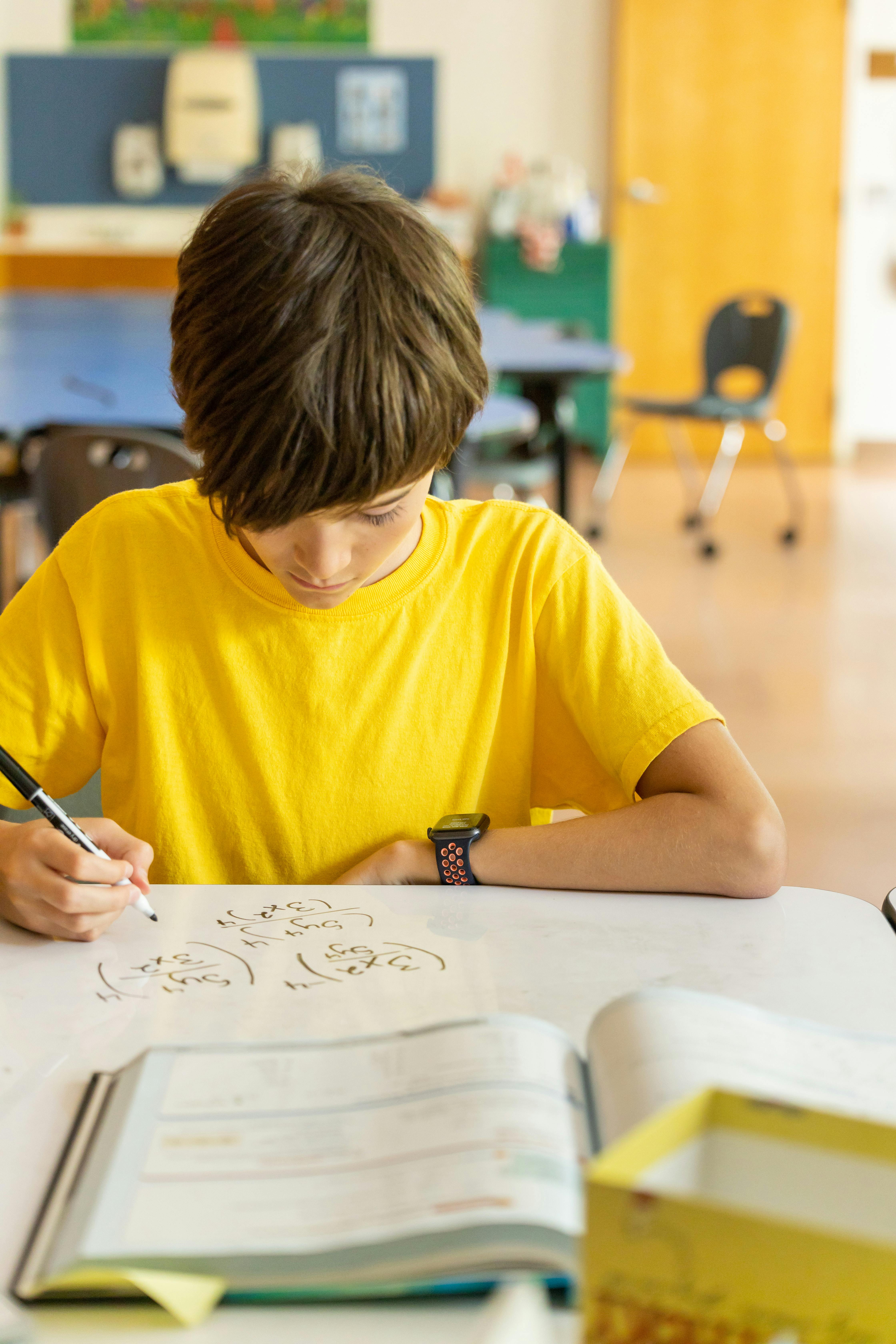 Child drawing on paper at a desk in a classroom