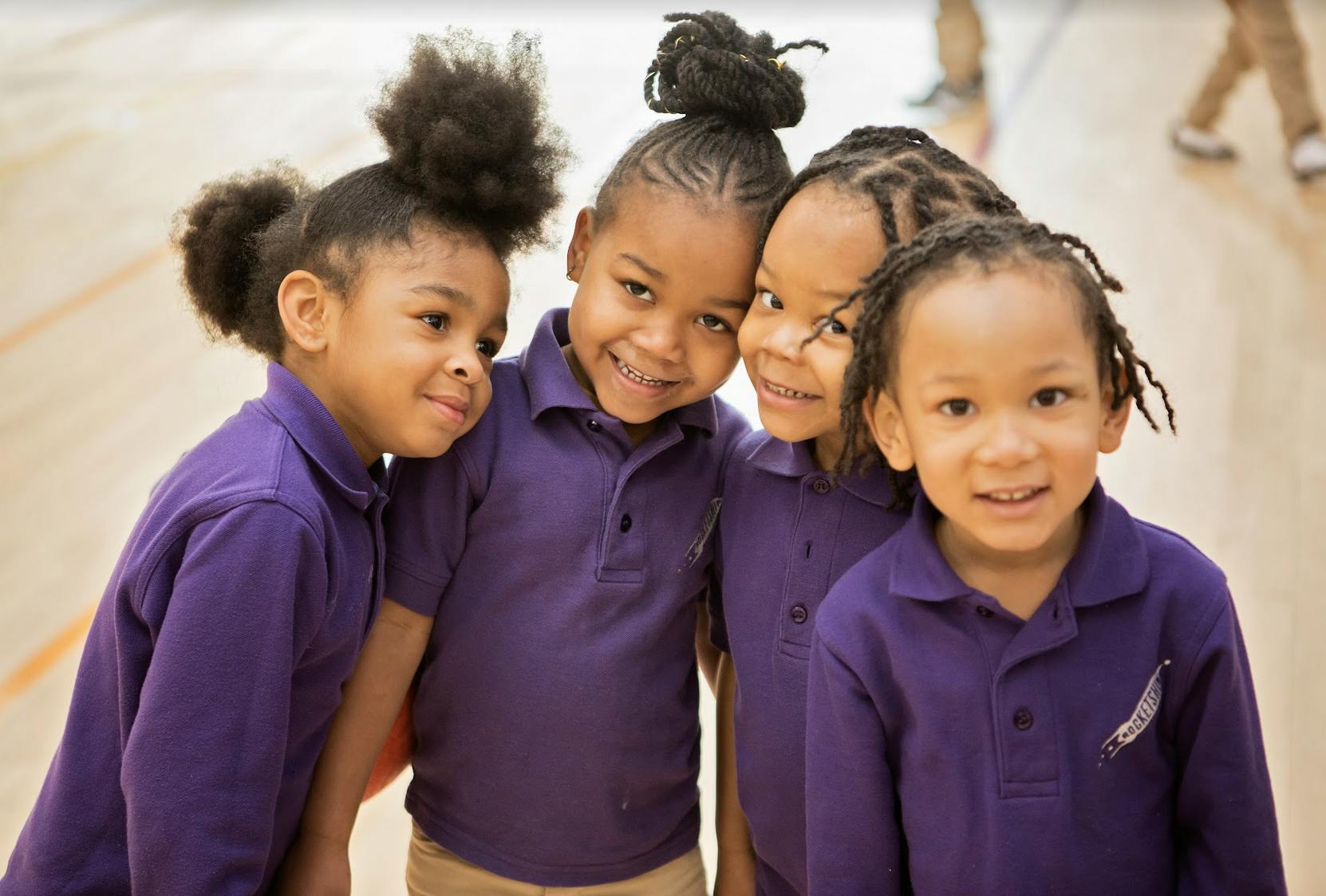Four children in purple shirts standing close together