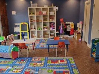 Playroom with small tables and chairs, toy shelf, and play tunnel