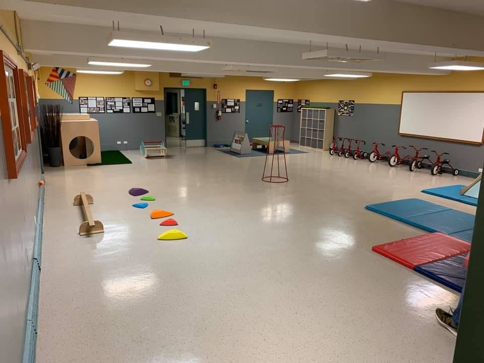 Empty classroom with play equipment, tricycles, and mats