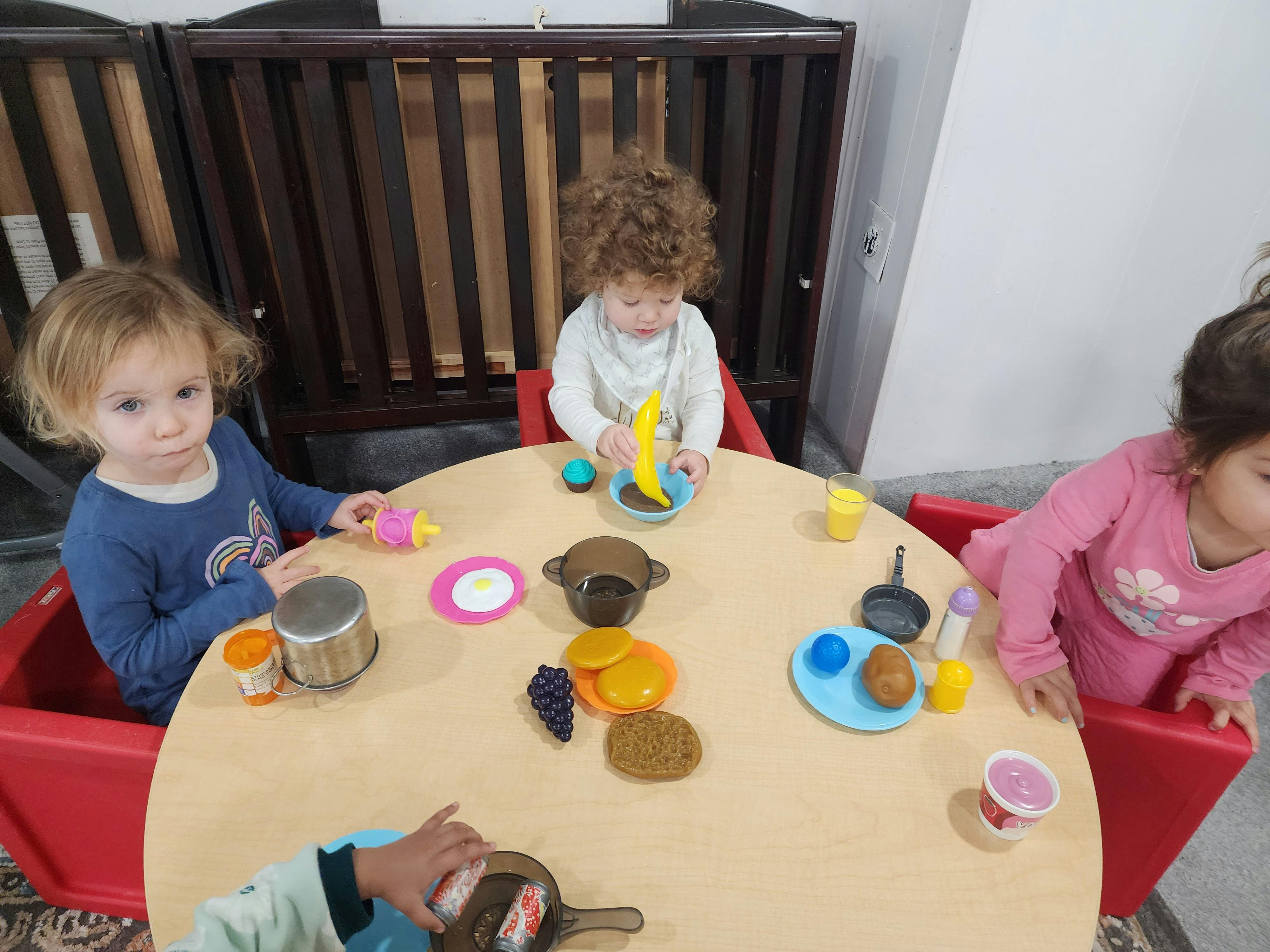 Three children playing with toy food at a table