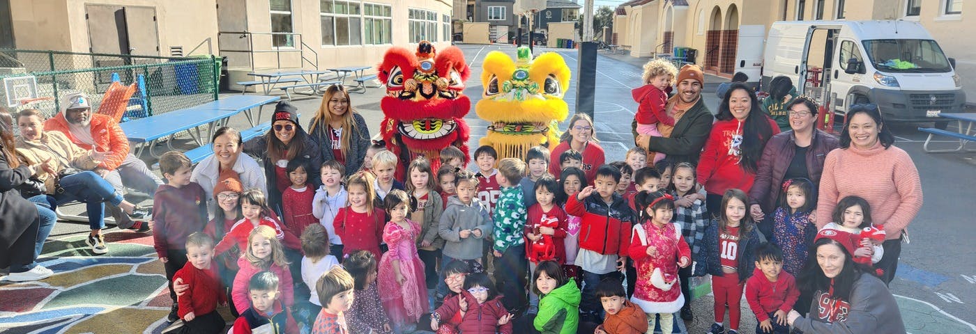 People and children posing with two lion dance costumes