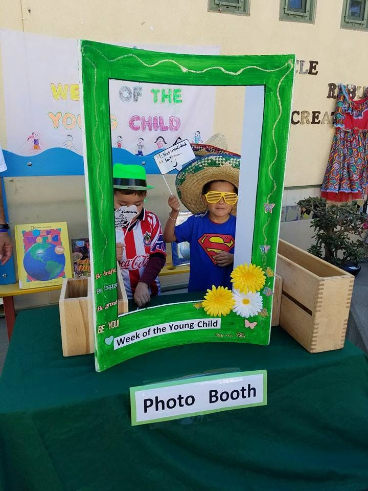 Two children posing in a photo booth frame with "Week of the Young Child" text