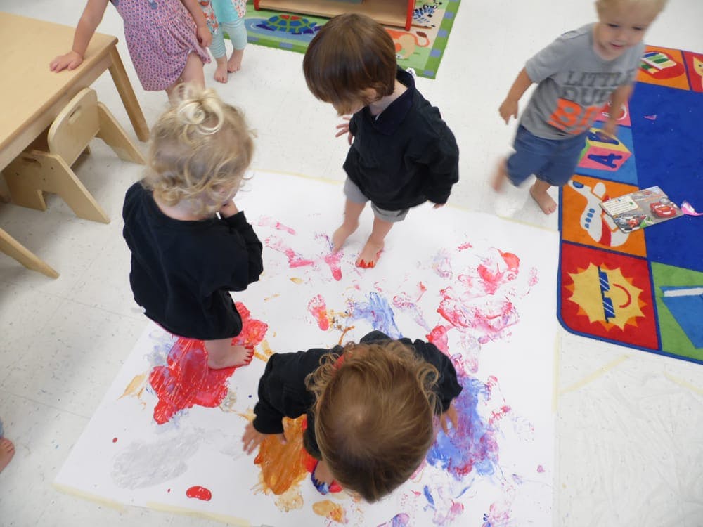 Children finger painting on a large sheet of paper