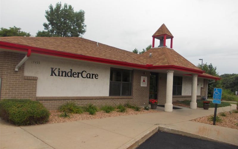 KinderCare building with brick and white siding, red gutters, and a small bell tower
