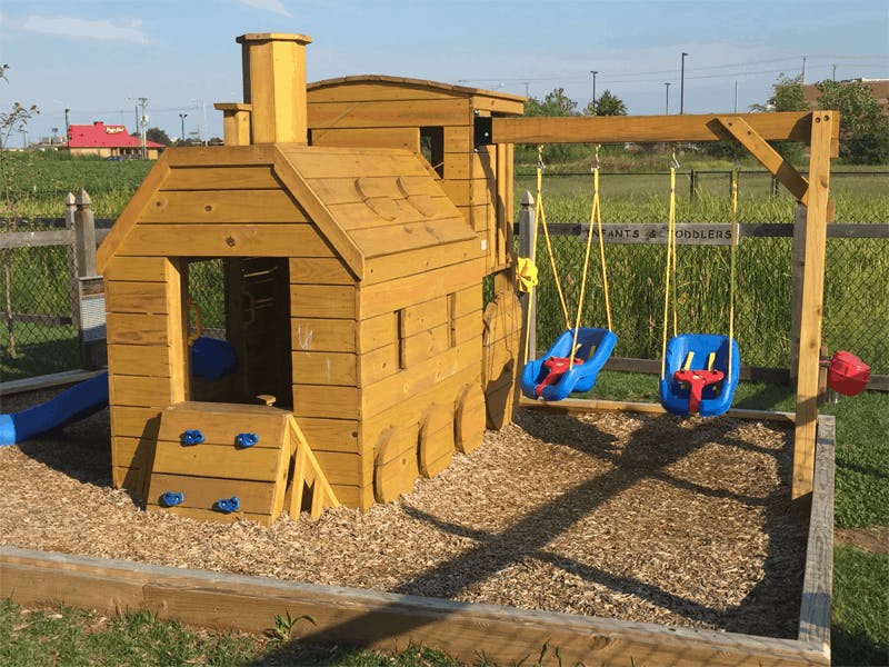 Wooden train-shaped playground structure with swings