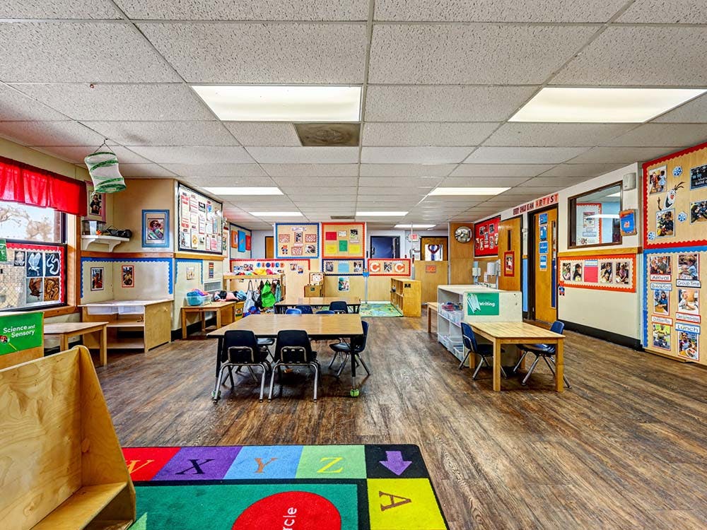 Empty colorful children's classroom with tables and chairs