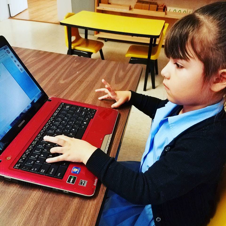 Child typing on a red laptop
