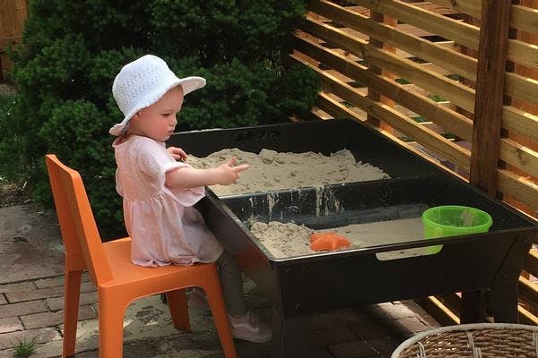 Child in a hat playing with sand and water table