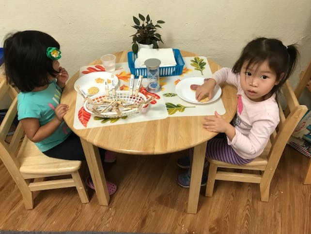 Two children sitting at a small table with plates