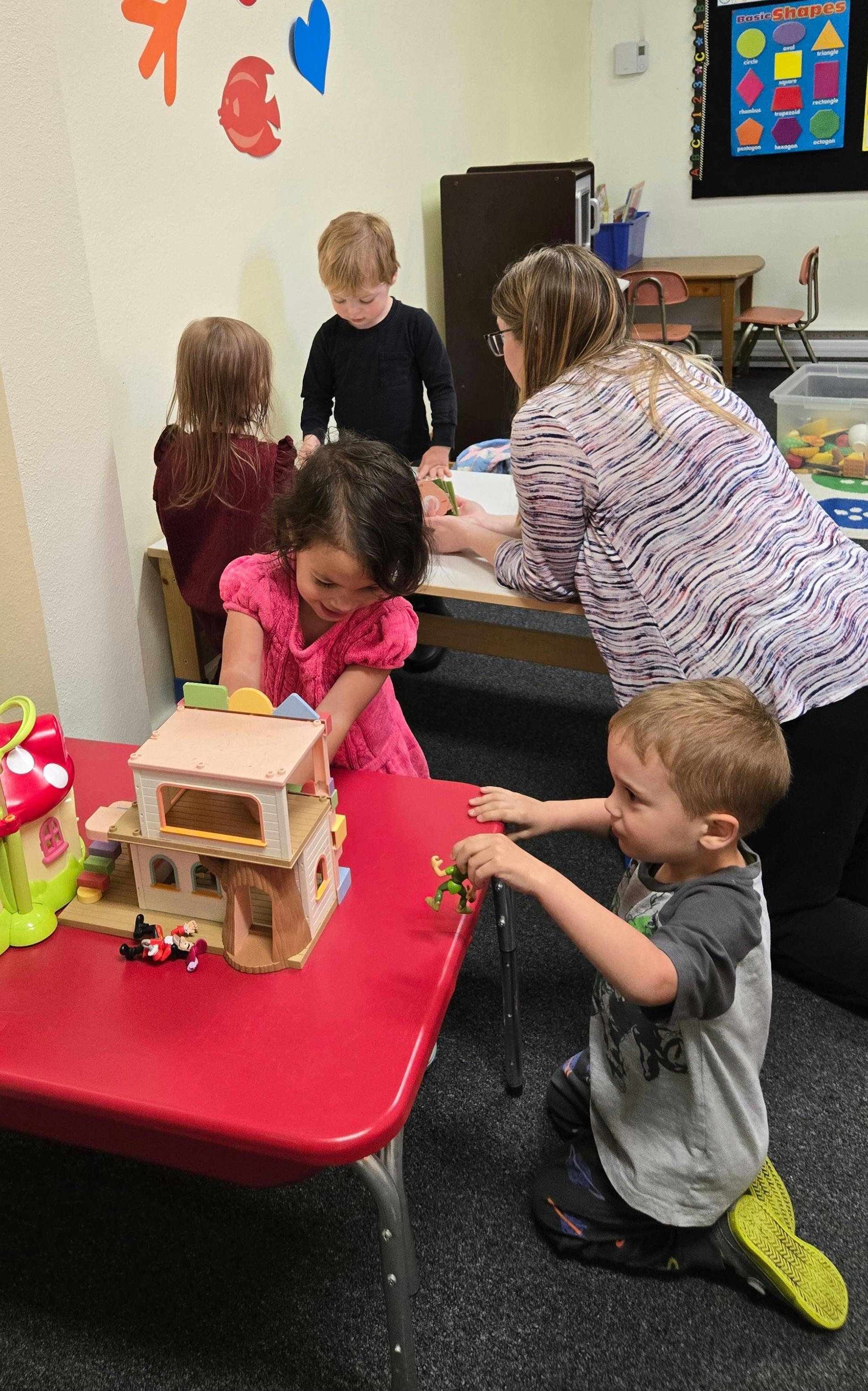 Adult and children playing with toys in a classroom