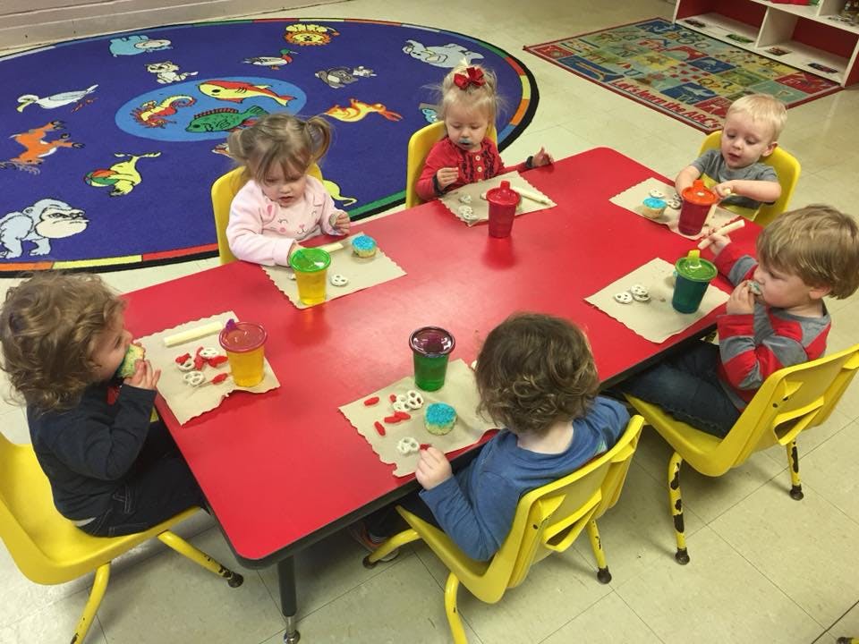 Children sitting at a red table with drinks and snacks