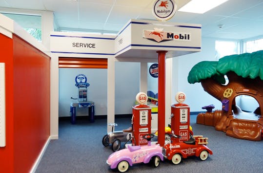 Play gas station with toy cars and pumps, in the background, a play service bay