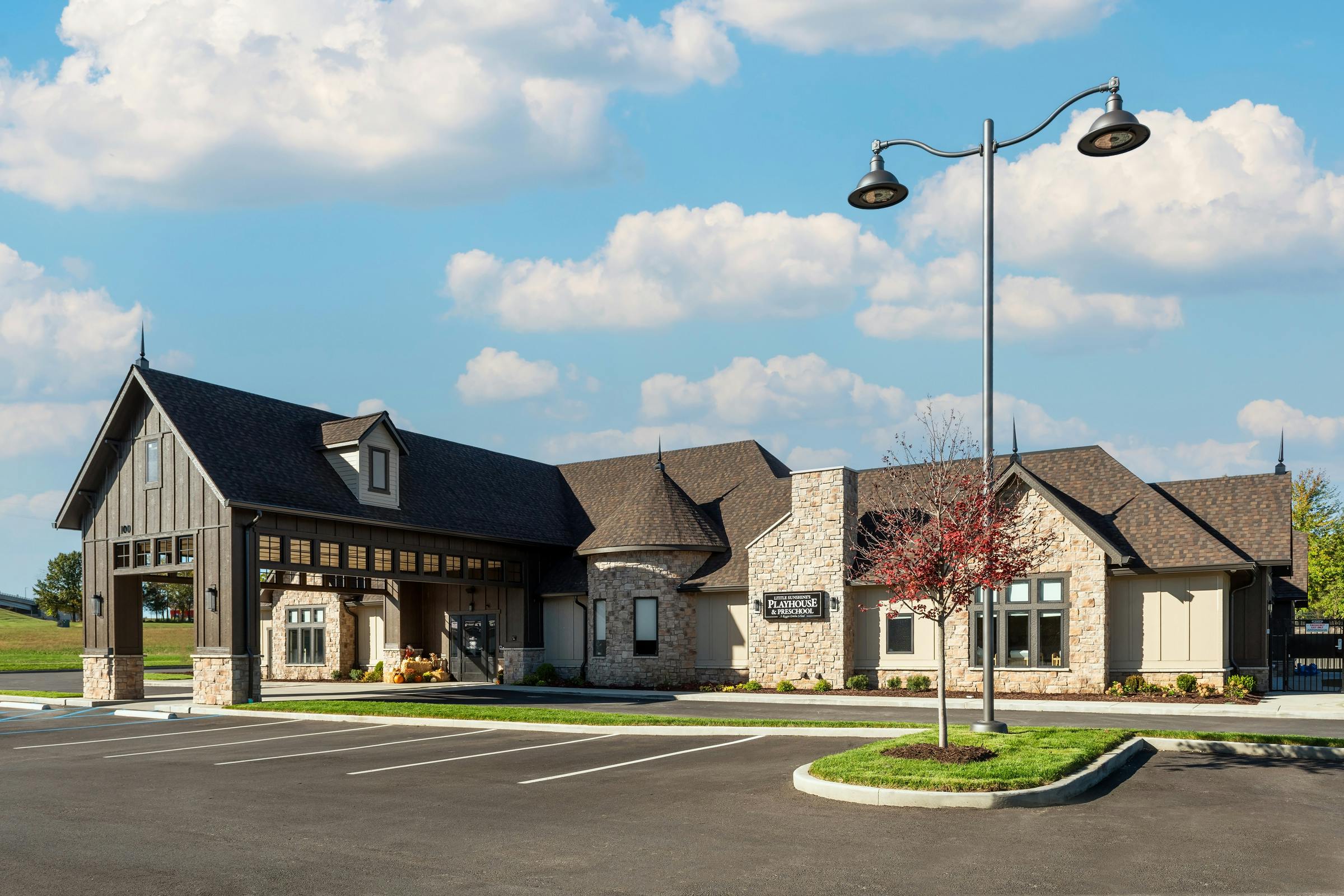 Building with stone and wood siding, a covered entrance, and a parking lot