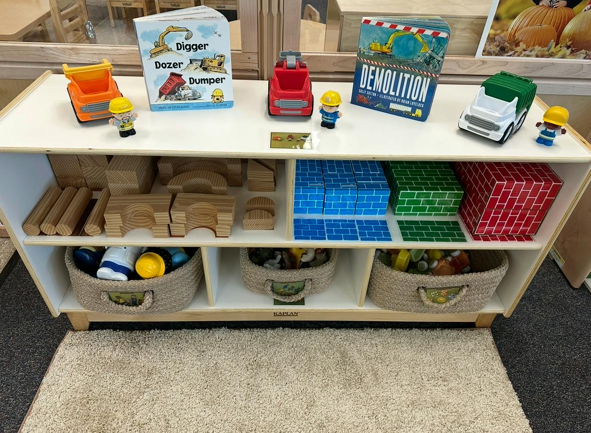 Shelf with toy construction vehicles, blocks, and baskets of toys