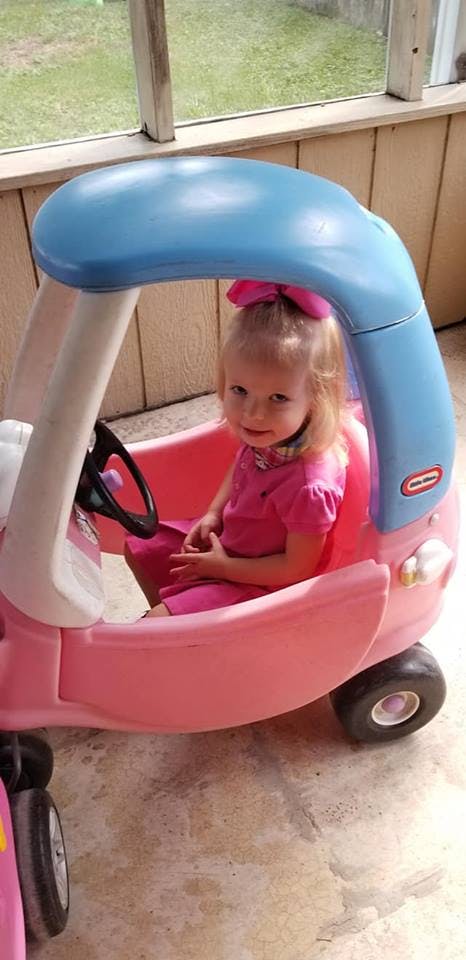 Child in a pink toy car