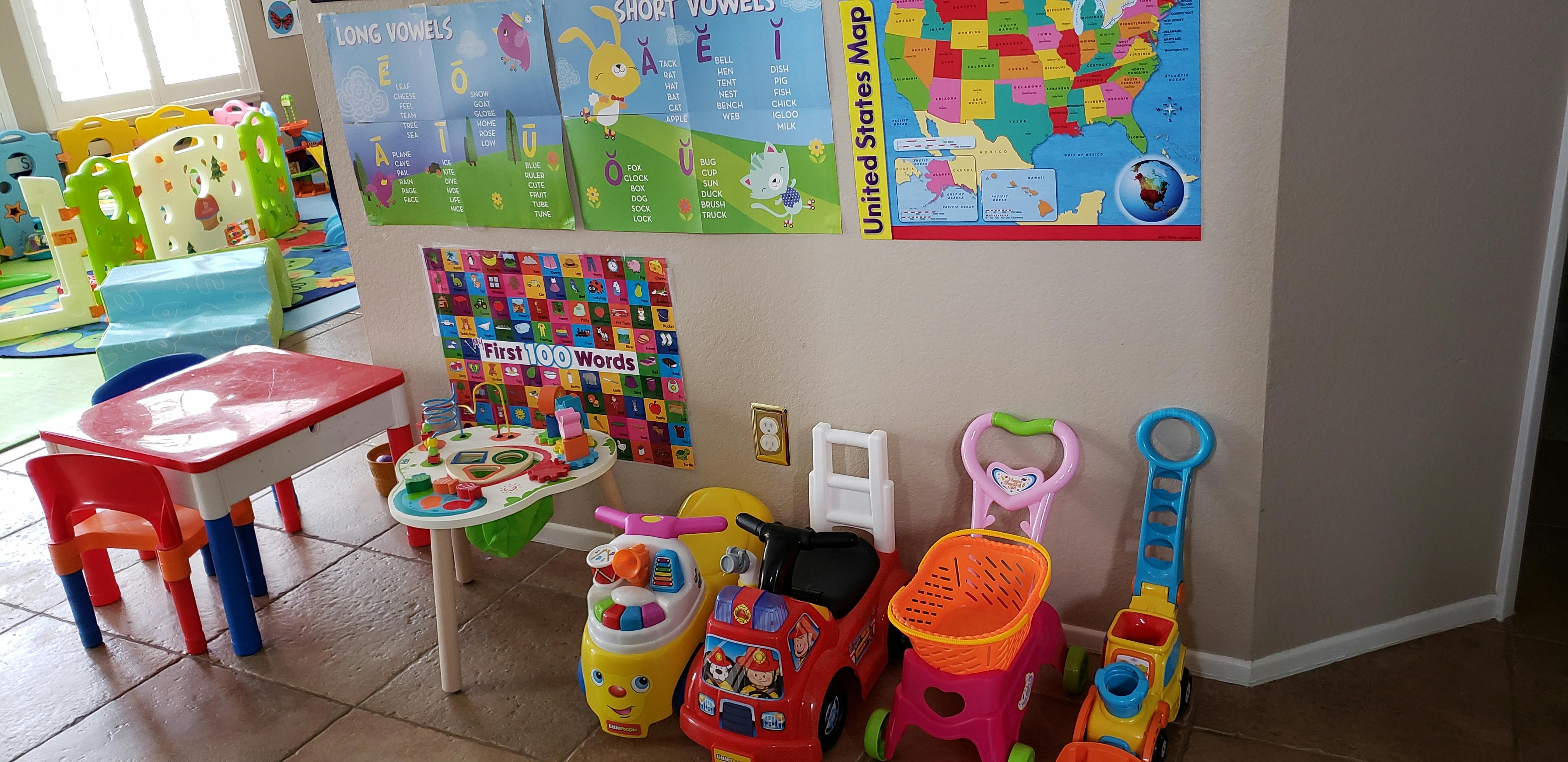 Children's play area with small table and chairs, toys, and wall charts