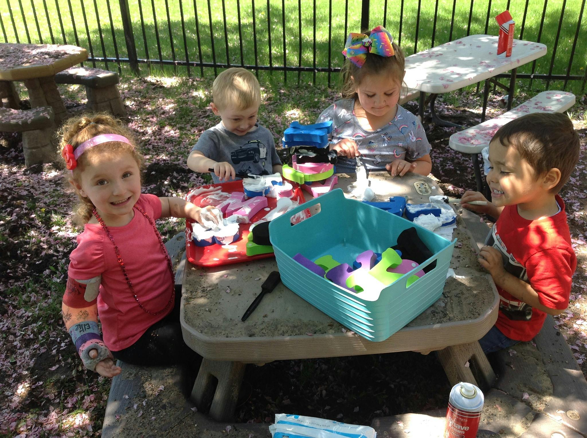 Four children sitting around a picnic table with toys