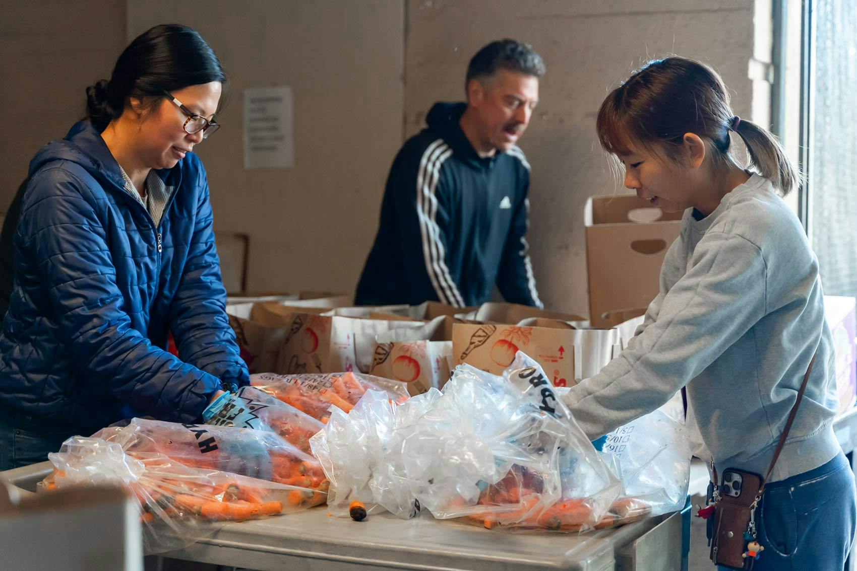 People sorting bags of carrots on a table