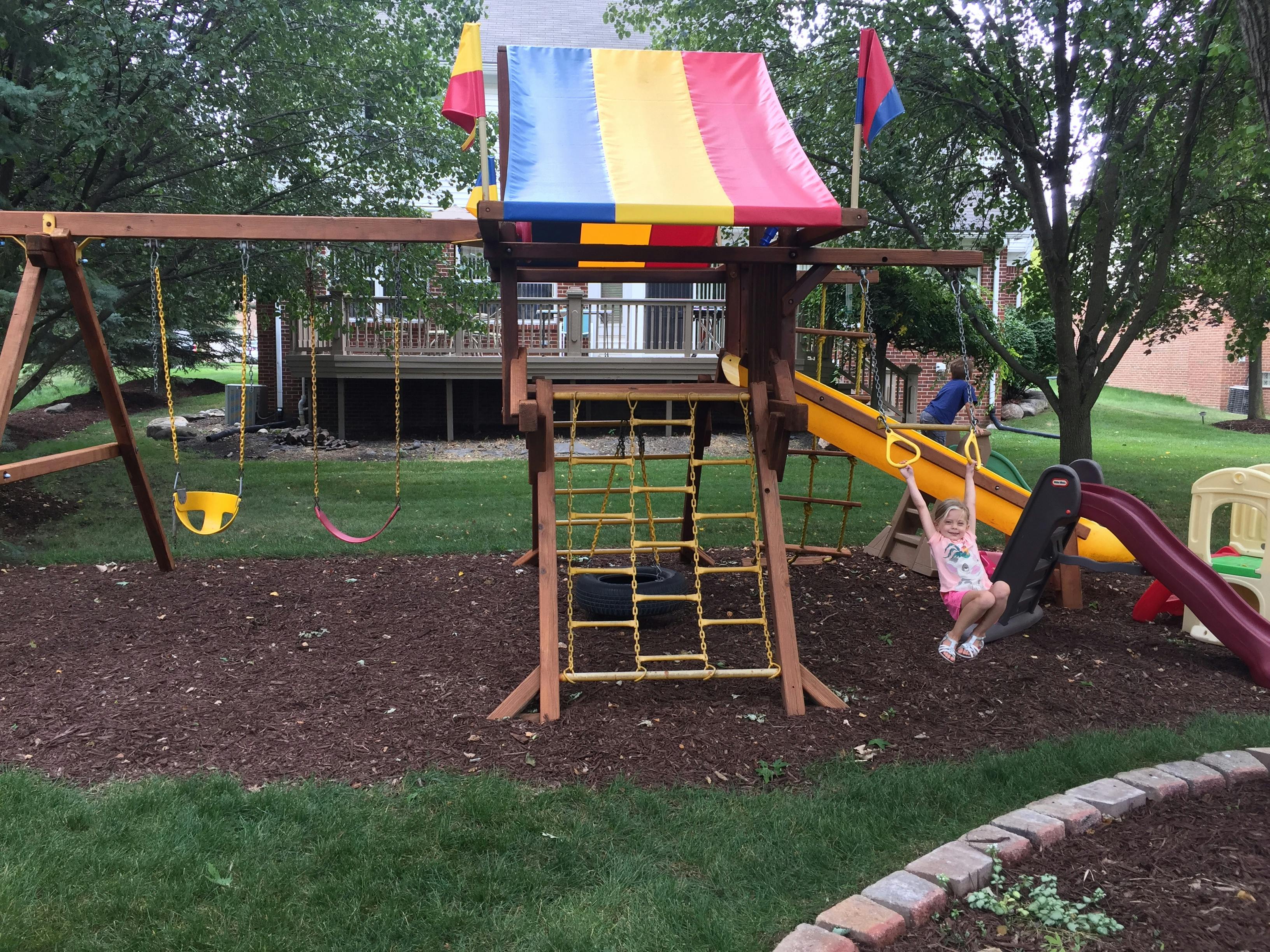 Child on a swing set with a slide and climbing net