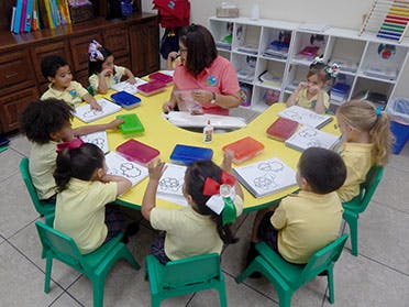 Adult and children seated around a table with books and art supplies
