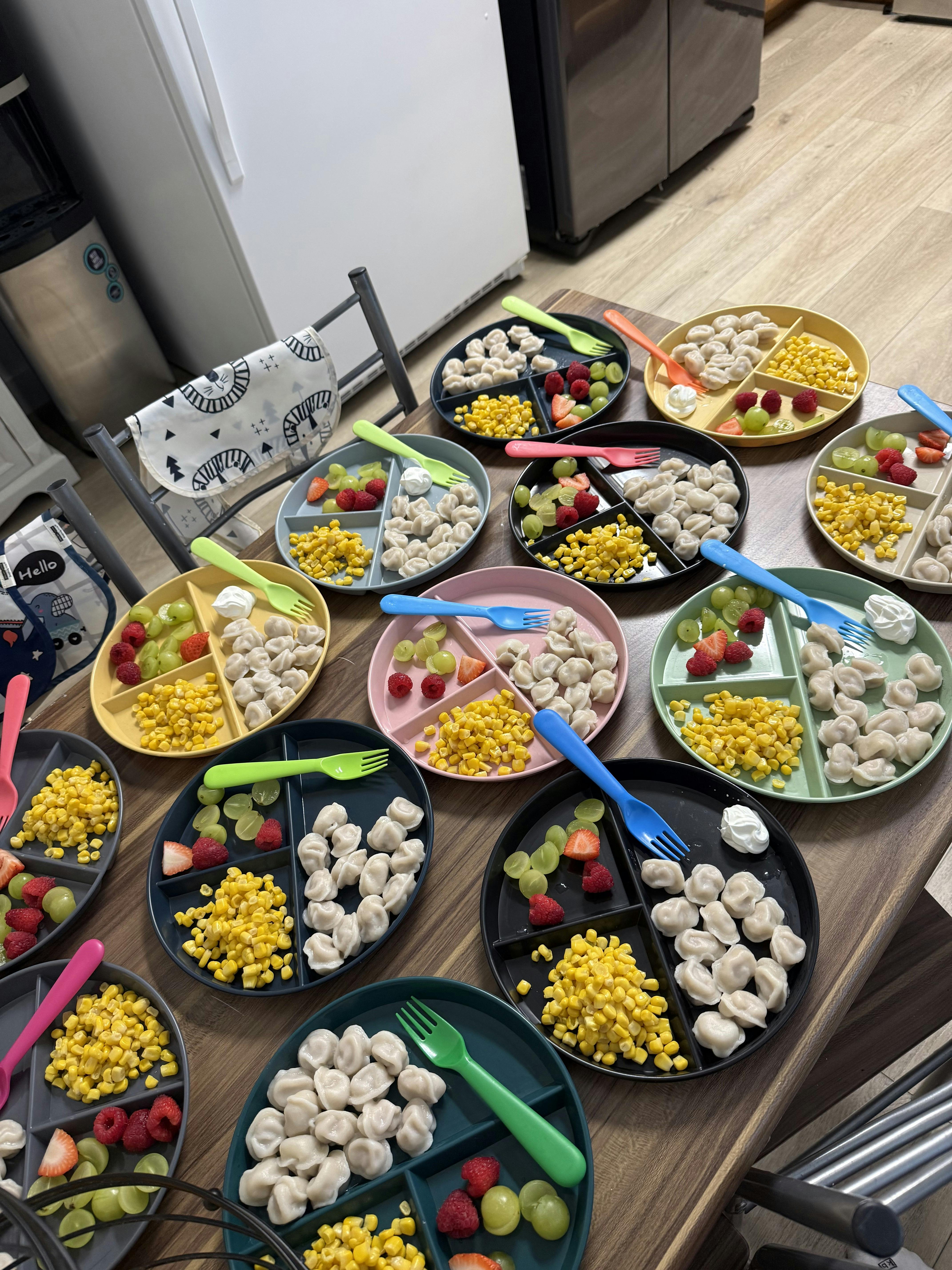 Several plates of food containing dumplings, corn, grapes, and berries