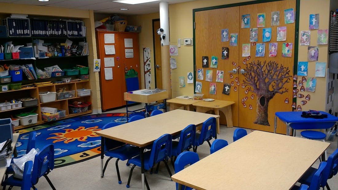 Classroom with tables, chairs, and a tree mural on the wall