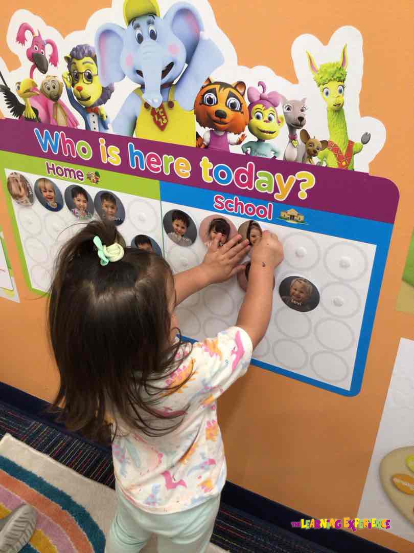 Child placing a photo on a "Who is here today?" board