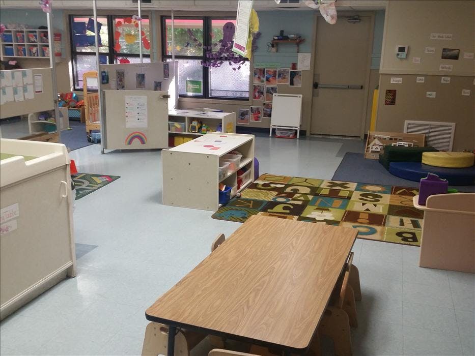 Empty classroom with small tables, chairs, and learning materials