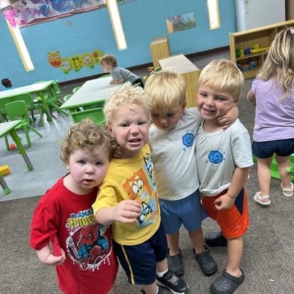 Four children standing together in a classroom
