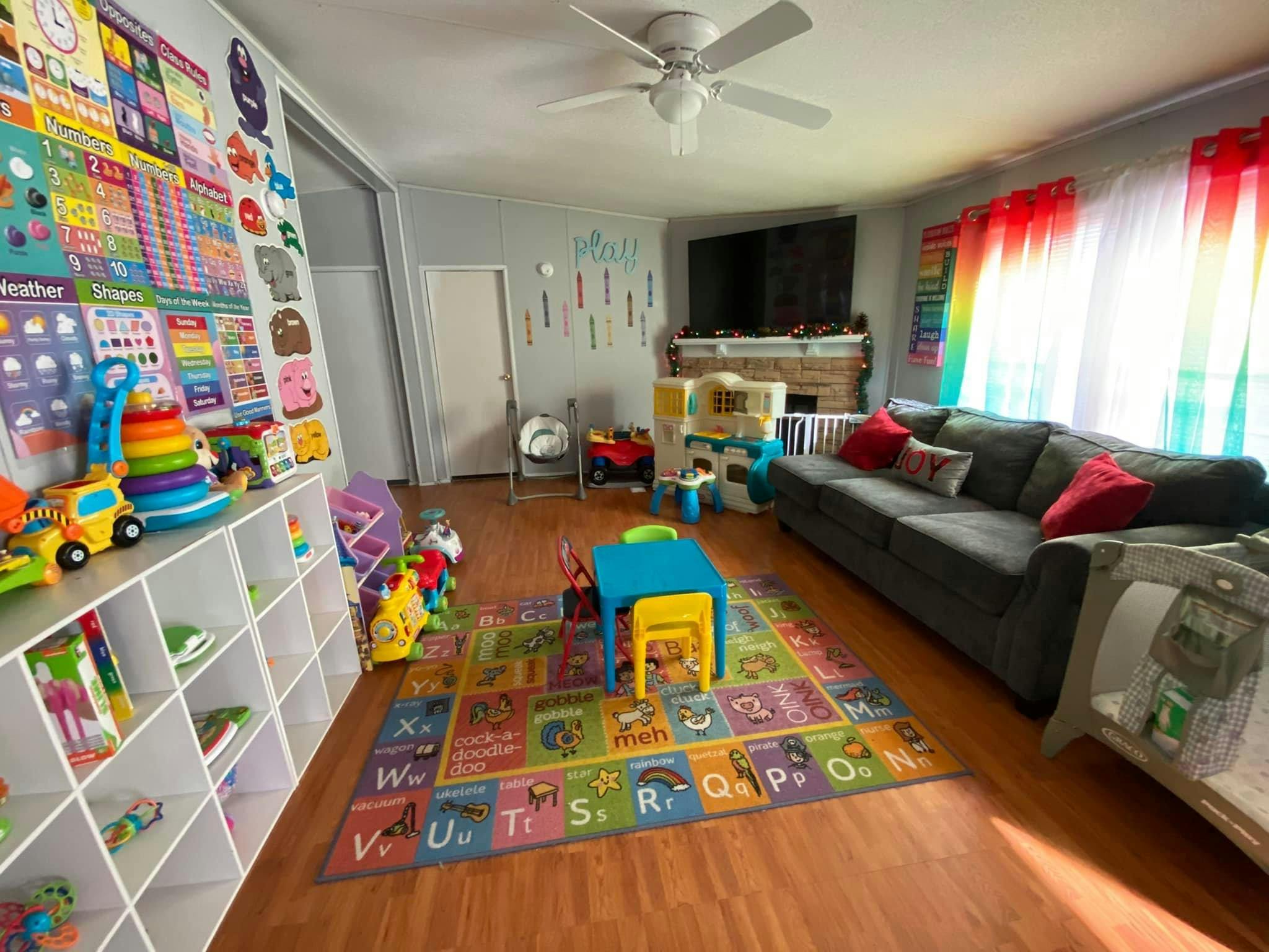 Playroom with a colorful alphabet rug, small blue table, and white shelves of toys
