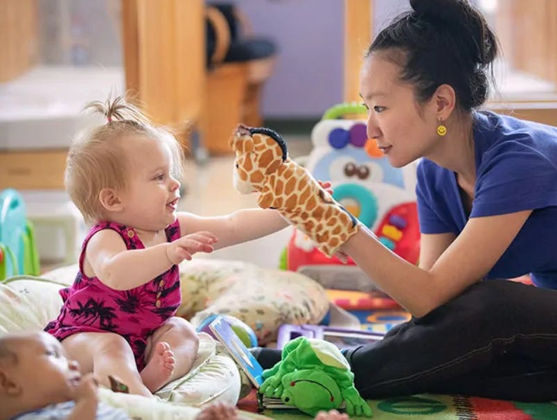 Person holding a giraffe puppet for a child
