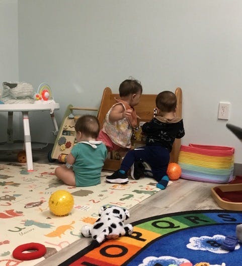 Three children playing on the floor in a room with toys