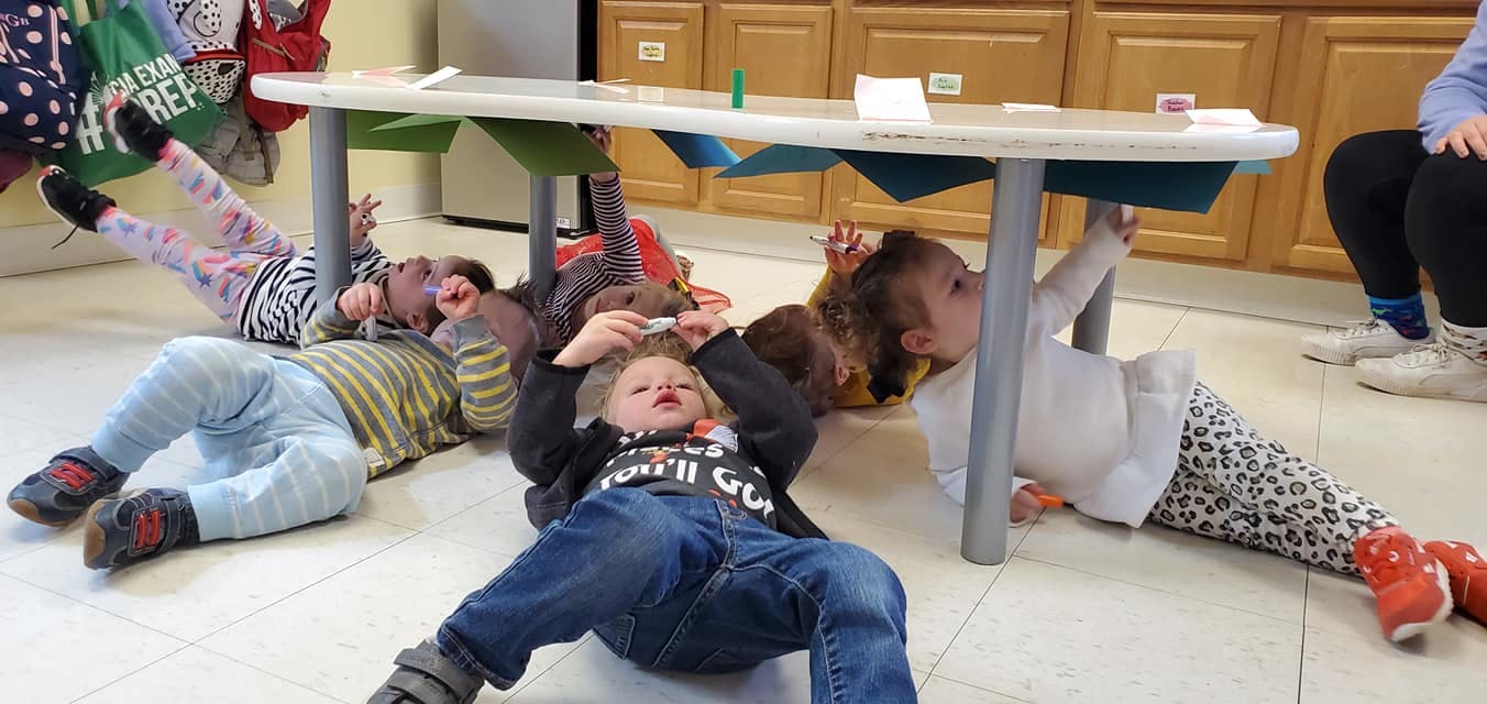 Children lying on the floor under a table