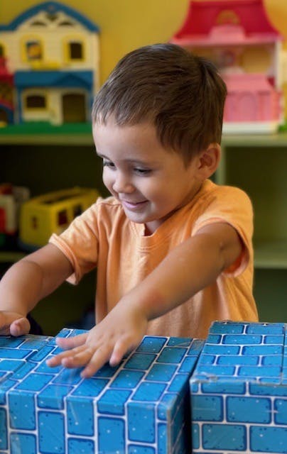 Child playing with blue brick-patterned blocks