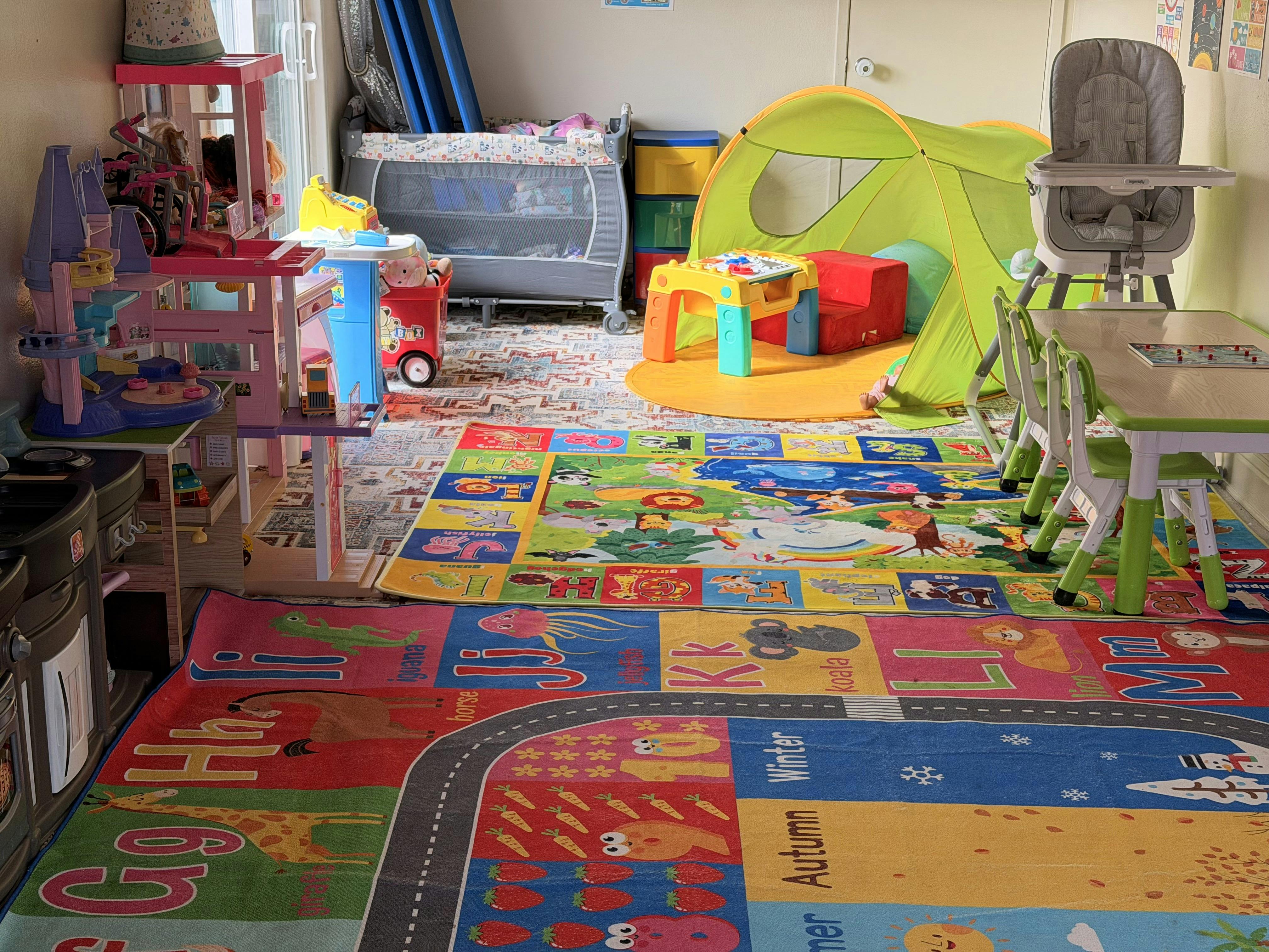 Colorful playroom with play tents, activity tables, and alphabet rugs