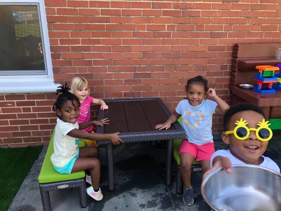 Four children playing around a table outdoors