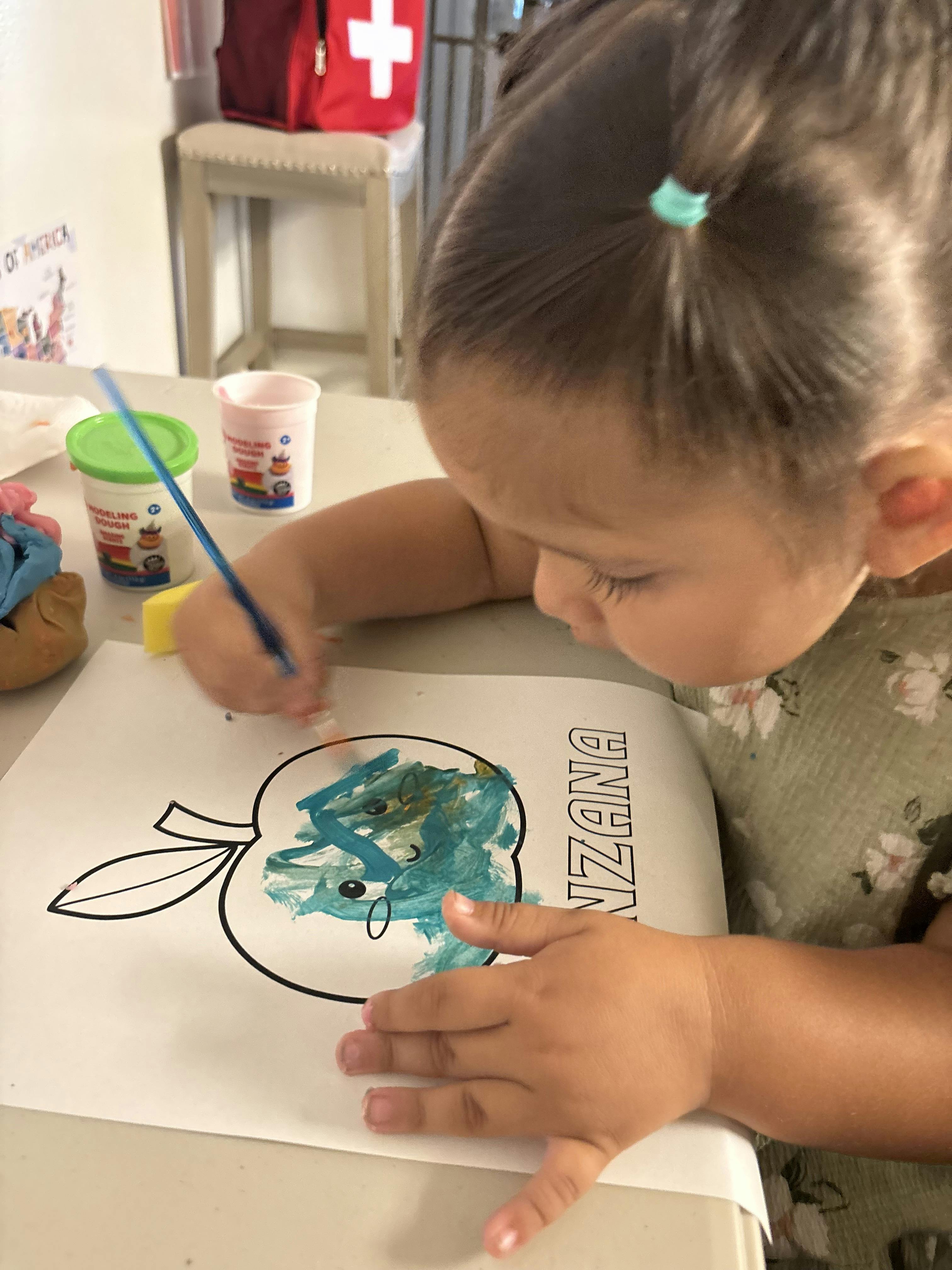 Child painting an apple outline on paper