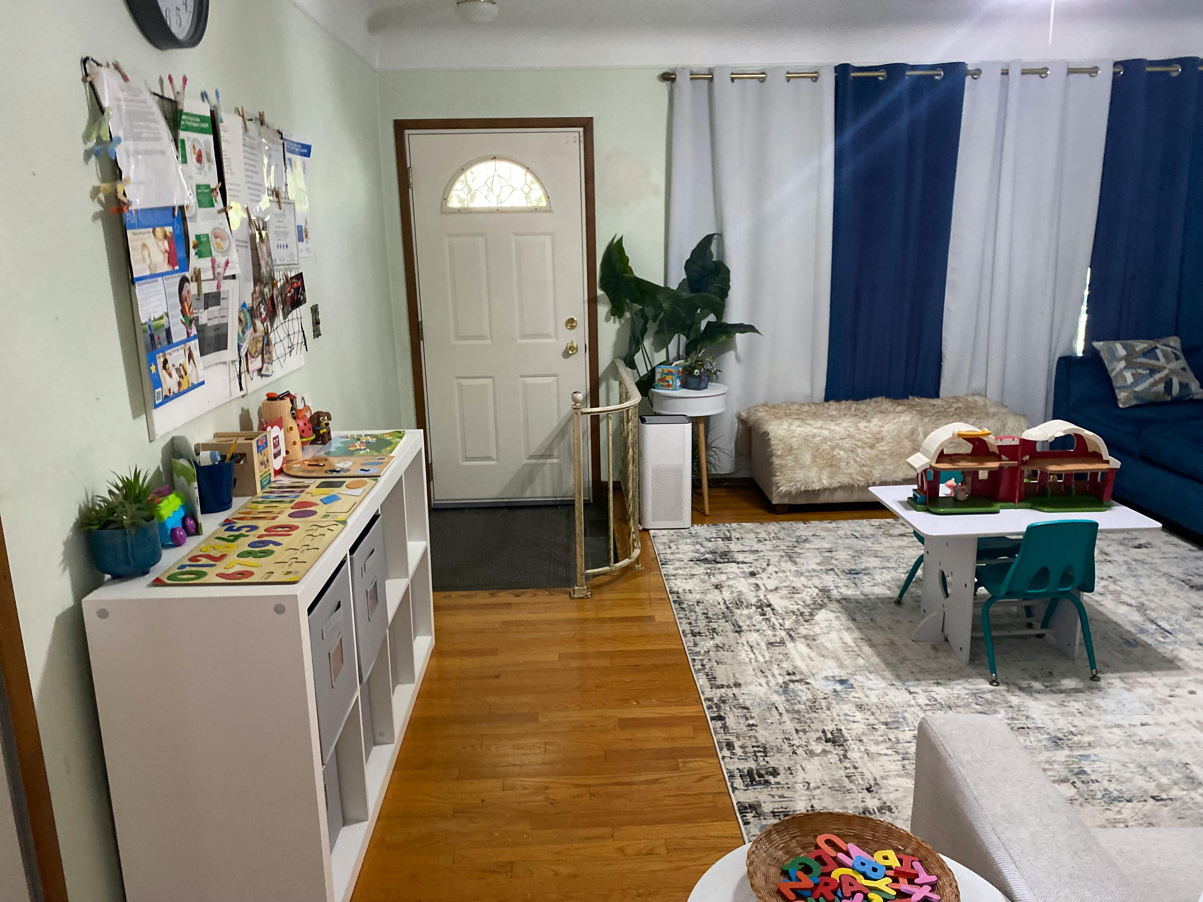 Living room with a white door, blue and white curtains, and a small table