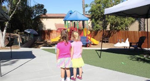 Two children standing on a path looking at a playground
