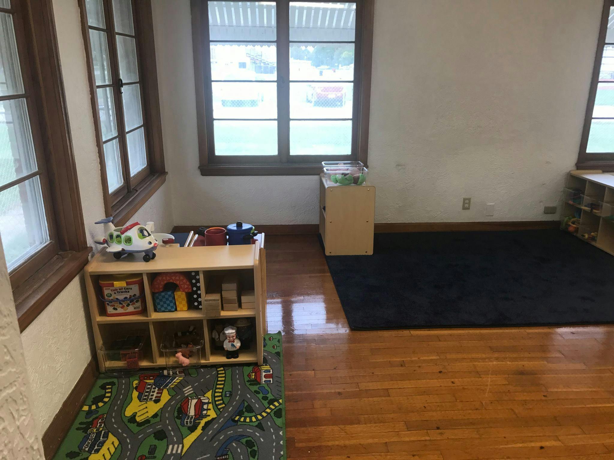Playroom with toy shelf, road rug, and windows
