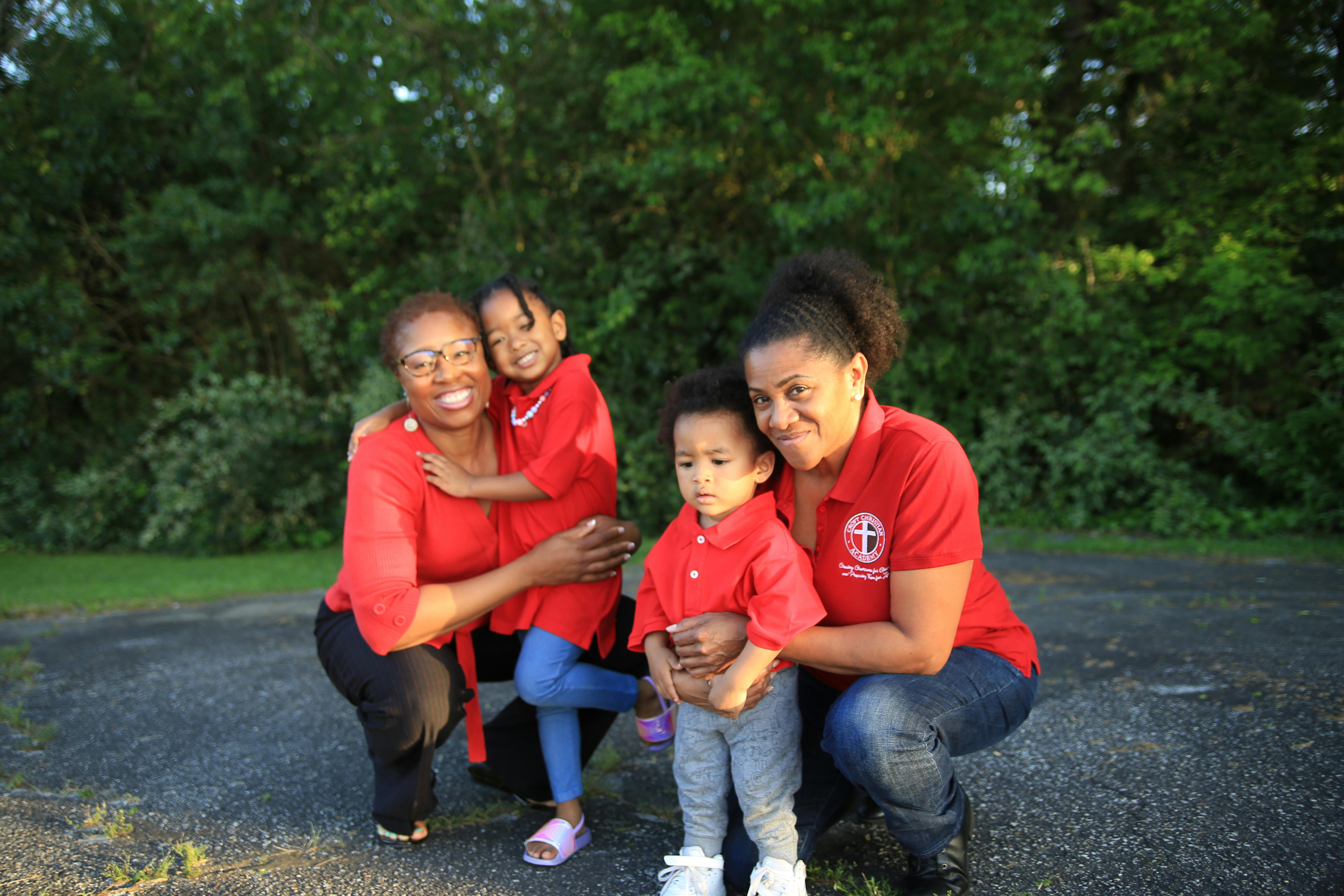 Two women with two children, all wearing red shirts