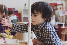 Child in plaid shirt reaching for a toy
