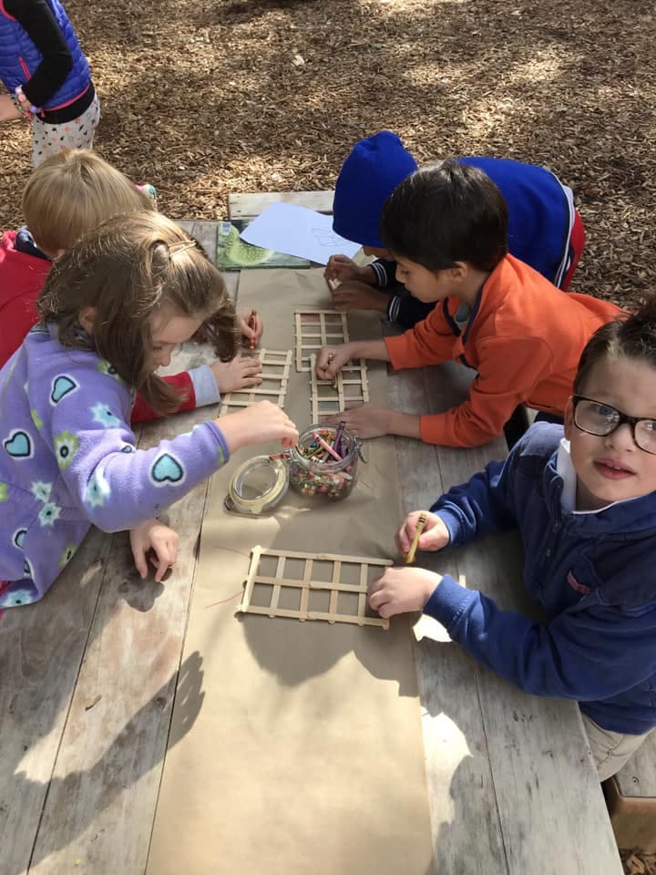 Children building structures with craft sticks on a wooden table