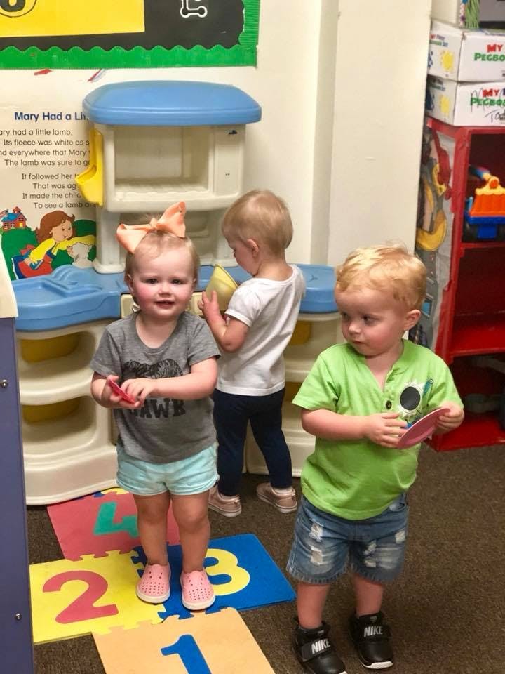 Three children standing in a classroom