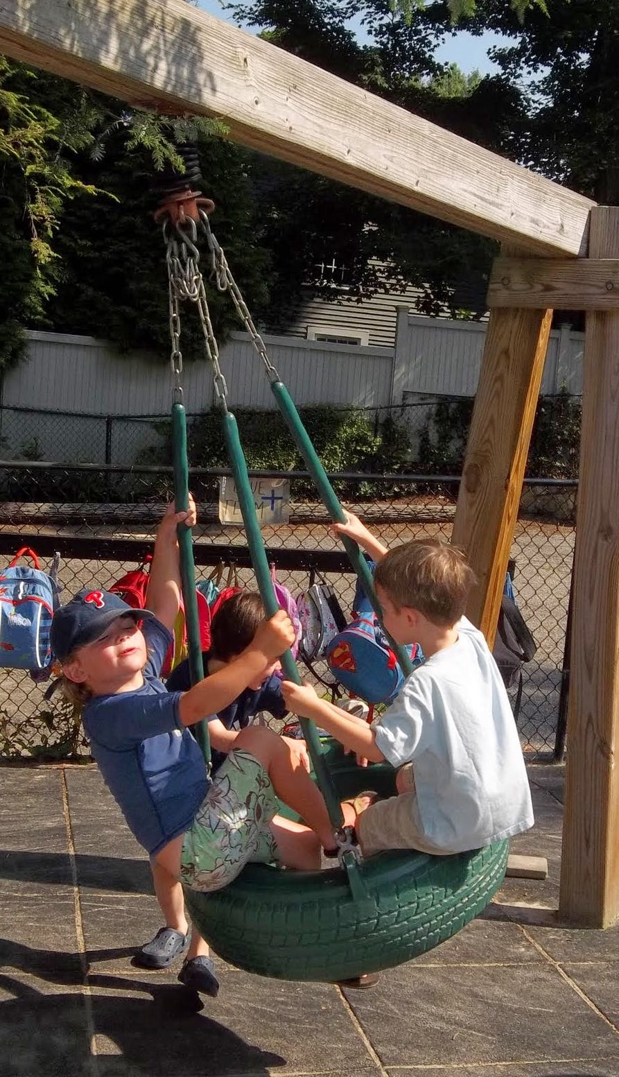 Three children playing on a tire swing