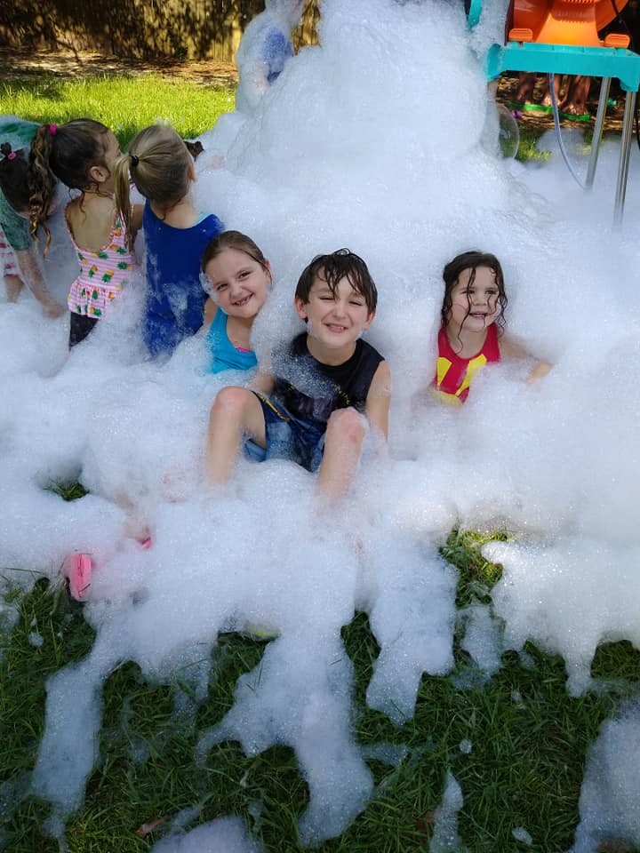 Children playing in a large pile of white foam outdoors
