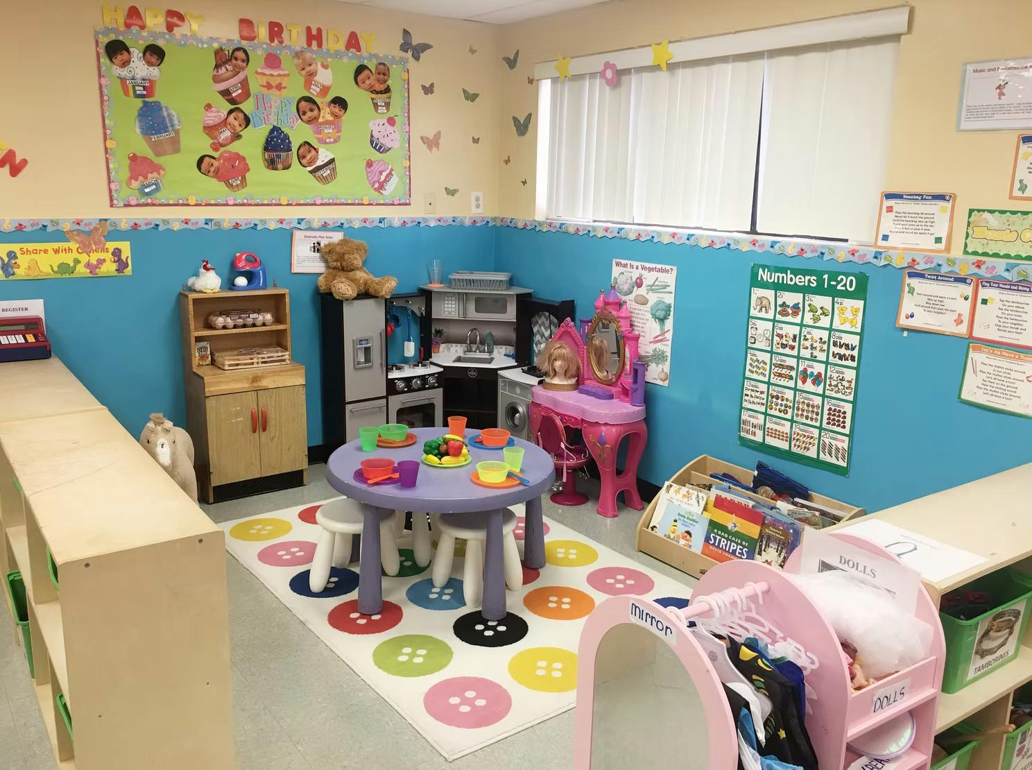 Children's play area with small table and chairs, toy kitchen, and dress-up vanity